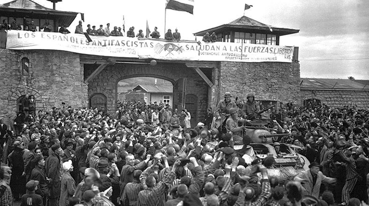 Prisioneros de Mauthausen saludan a la 11ª División Acorazada de los EE UU por su liberación bajo una pancarta escrita en español.